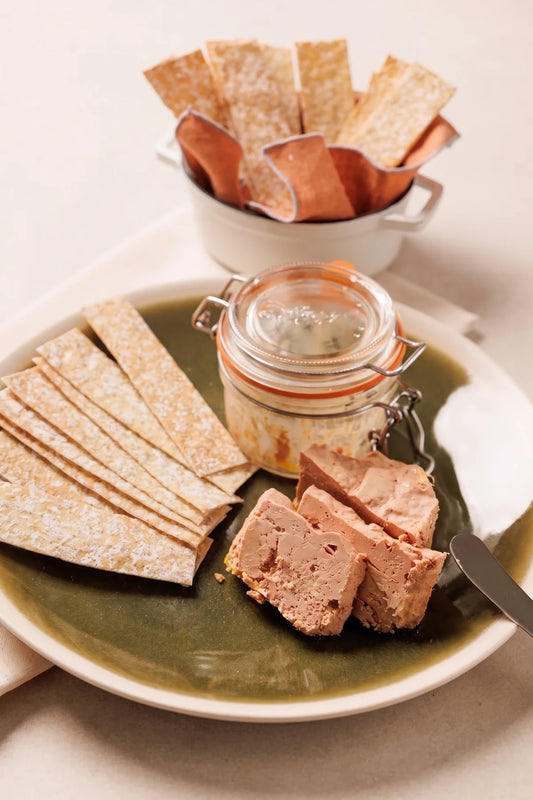 Bocal de foie gras de pato mi-cuit con láminas de pan crujiente y lonchas servidas en el plato